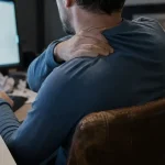 Douleur entre omoplates dos : posture au bureau, mains près des omoplates
